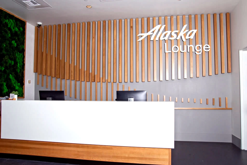 Wood wall sign with the words Alaska Airlines hanging in the Alaska Airlines lounge at SEA airport D concourse in SeaTac, WA, fabricated and installed by contractor Construction Expeditors, Edgewood, WA.