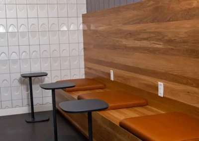 Custom wood bench seating with power outlets, personal tables, and tiled walls.