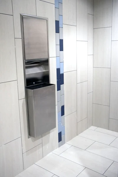 Renovated lobby bathroom with tiled floors, tiled walls, and a paper towel dispenser/trash receptacle fixture at Holiday Inn Yakima. 