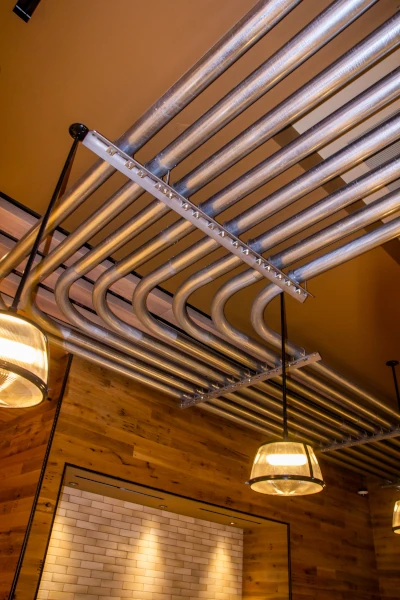 Close-up of custom metal framing and metal beer chutes suspended from the bar’s ceiling.