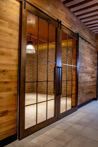 Custom glass barn doors with wood trim and rustic metal door handles. 